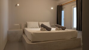 A bedroom with a bed, pillows, and a window with curtains.