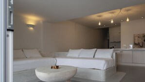 Un salon moderne et minimaliste, avec un canapé, une table basse ronde et des luminaires suspendus.