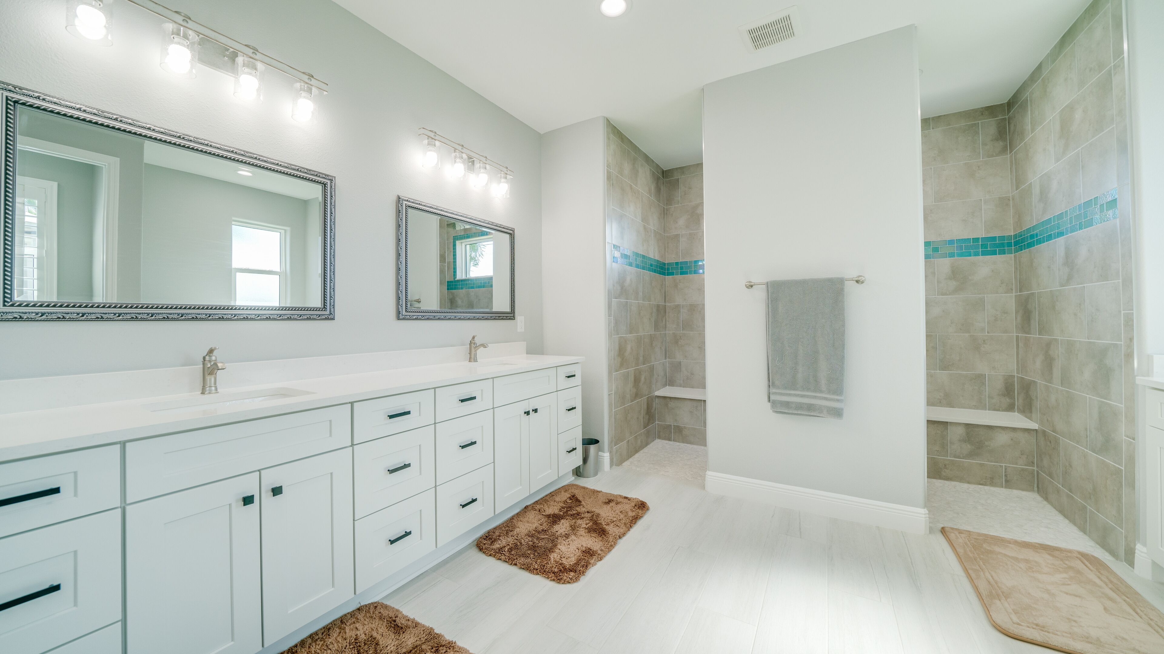 A modern bathroom with a white vanity, two mirrors, a shower, and a towel rack.