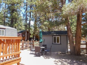 Une cabane avec une terrasse, un espace salon extérieur et un petit abri de jardin.