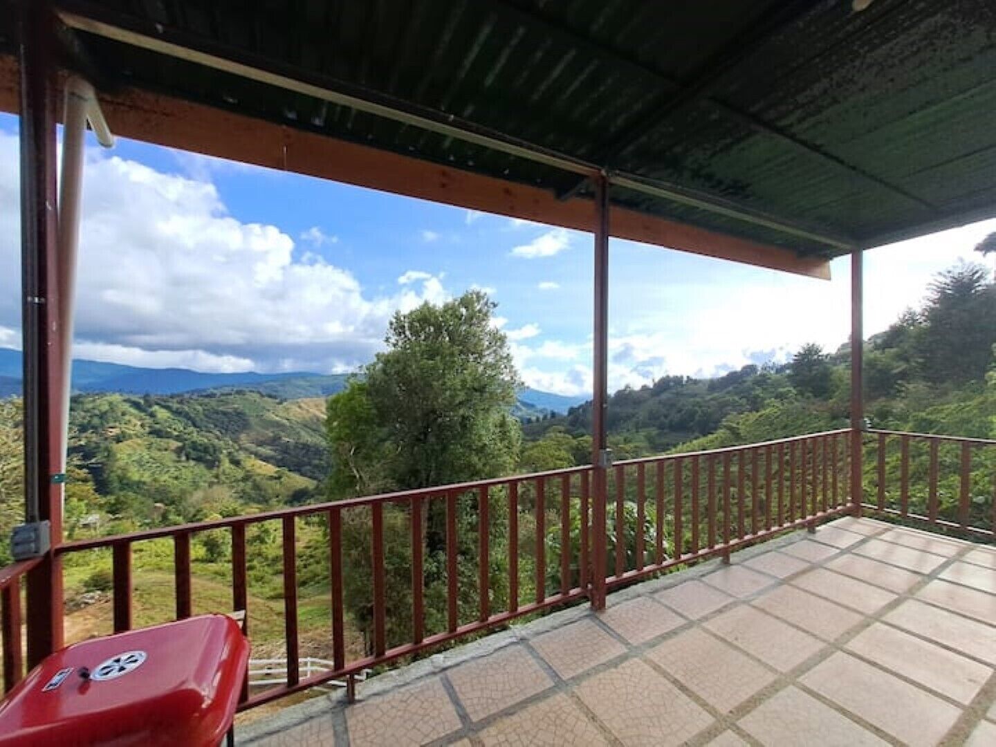A covered balcony with a view of a mountainous landscape.