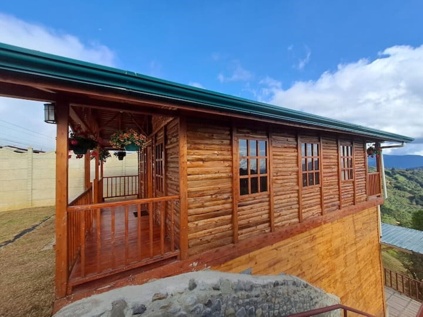 Una baita di legno con un balcone, ampie finestre e vista sul paesaggio circostante.