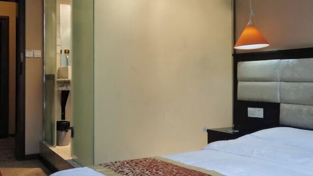 A hotel room with a bed, a nightstand, a mirror, and a hanging lamp. - Sanbao Ruixiang Business Hotel (Daofu)