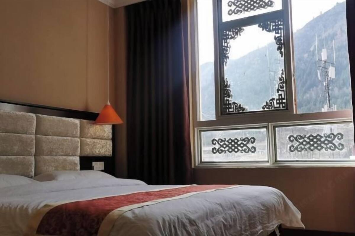 A bed with a headboard, a window with decorative glass, and a view of a mountain.