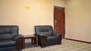 A room with two black leather chairs, a small wooden table, and a patterned carpet. - Sanbao Ruixiang Business Hotel (Daofu)