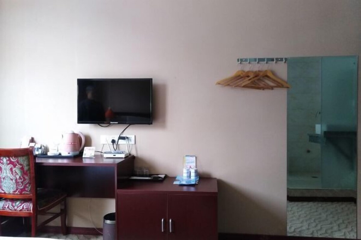 Une chambre d’hôtel équipée d’un bureau, d’un téléviseur fixé au mur, d’une armoire et d’un miroir.