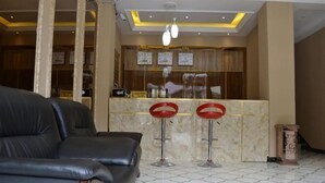 A lobby with a black leather sofa, a reception desk with a marble counter, and a patterned floor. - Sanbao Ruixiang Business Hotel (Daofu)