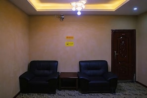 A room with two black leather chairs, a small table, a wooden door, and a ceiling light fixture. - Sanbao Ruixiang Business Hotel (Daofu)