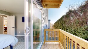 A room with a large sliding glass door leading to a balcony with a wooden railing.