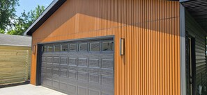 A building with a garage door, vertical siding, and a metal roof.