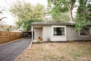 A single-story house with a covered porch, a small front yard, and a wooden fence. - King Bed - 2 Twin Beds - Retro 1948 Mid-century Metal Lustron - 2 car garage (Des Moines)