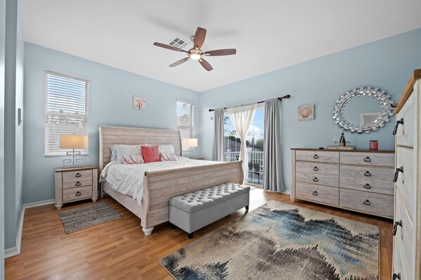 A bedroom with a bed, a bench, a dresser, a ceiling fan, and a window with blinds.