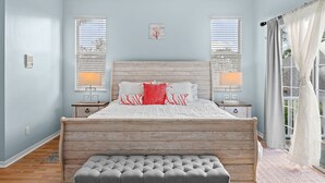 A bedroom with a wooden headboard, two bedside lamps, a bench, and a window with blinds. - Luxury Family Getaway (Naples)