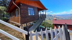 Eine Holzhütte mit Balkon, rotem Dach und Bergblick.