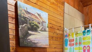 Ein Holzinterieur mit einem Hausgemälde, einem bunten Duschvorhang und einer Tür mit Schlüsselschloss.