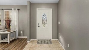 Un pasillo con una puerta blanca, un tapiz estampado y un candelabro.