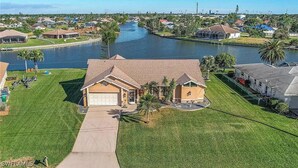 A residential area with a river, houses with sloped roofs, and a well-maintained lawn. - Waterfront Canal with Paddle boarding, kayaking, and fishing  (Cape Coral)