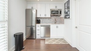A compact kitchen with white cabinets, stainless steel appliances, and a small countertop. - Fully Private Apartment - New Luxury Two Bed Private Apartment By The Lake (Mississauga)