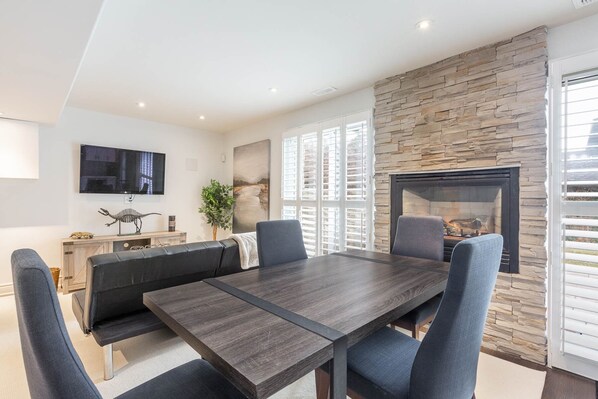 A modern dining area with a stone accent wall, a fireplace, and a television mounted on the wall.