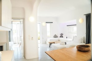 Un salon moderne et bien éclairé, avec une table en bois, un ensemble de canapés et un coin repas.
