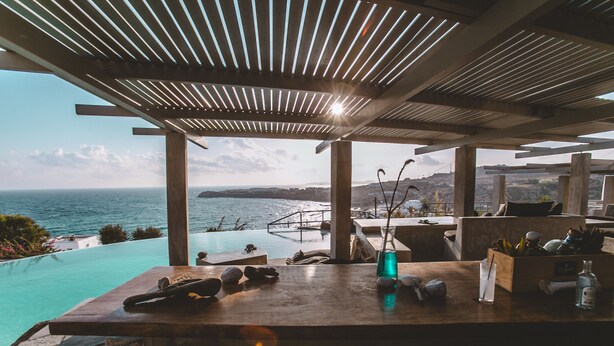 Un bar junto a la piscina con vista al océano y una isla distante.