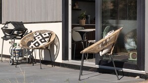 An outdoor seating area with two wicker chairs, a grill, and a table. - Private suite 2 bedroom in the Southern Okanagan BC reg #H082210588 (Oliver)