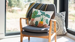 A modern chair with a cushion, a patterned pillow, and a geometric rug in a room with large windows. - Private suite 2 bedroom in the Southern Okanagan BC reg #H082210588 (Oliver)