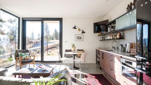 A modern kitchen with a large window, a dining area with a table and chairs, and a cozy seating area with a sofa and a coffee table. - Private suite 2 bedroom in the Southern Okanagan BC reg #H082210588 (Oliver)