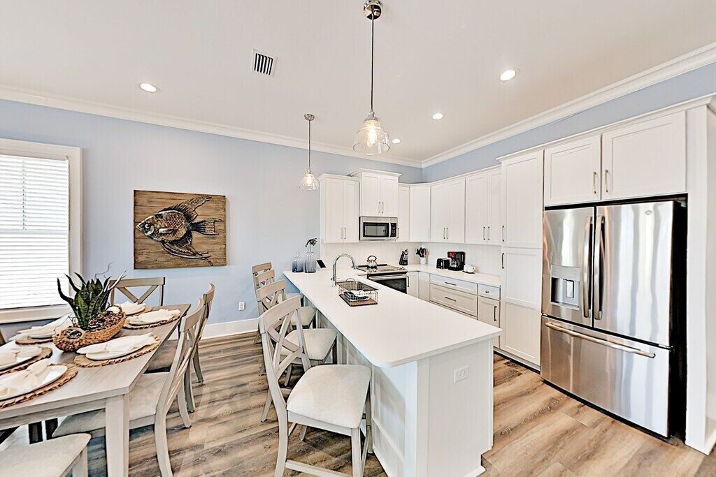 A modern kitchen with white cabinetry, stainless steel appliances, and a central island.