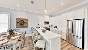 A modern kitchen with white cabinetry, stainless steel appliances, and a central island.