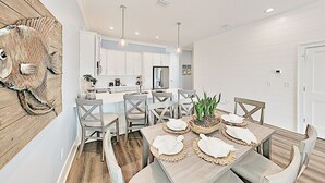 A modern kitchen with white cabinets, a central island, and pendant lighting.