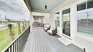 A covered porch with wicker chairs and a view of the street.