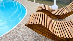 A poolside area with a wooden lounge chair and a stone-tiled deck. - Relax in Style at Our 3BR/2BA Retreat with Private Pool|Game Room|Fire Pit|Yoga (Tampa)