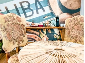 A room with floral-patterned chairs, a round woven table, and a wall with a large 'LIBA' sign. - Relax in Style at Our 3BR/2BA Retreat with Private Pool|Game Room|Fire Pit|Yoga (Tampa)