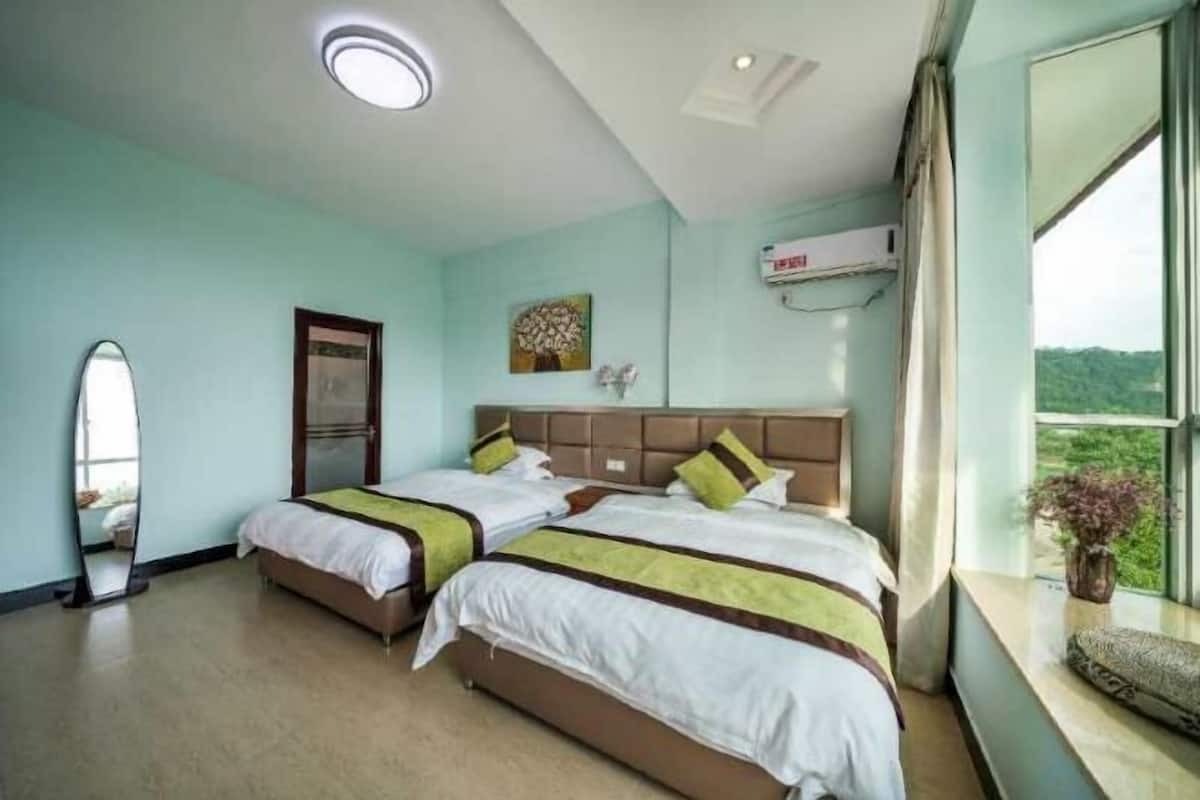 Habitación de hotel con dos camas, un ventanal con vistas, una lámpara de techo y un equipo de aire acondicionado.