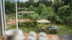 A patio area with a table and chairs, surrounded by lush greenery and a pergola structure. - Wuyi Mountain Ruilan Chasu (Wuyishan)