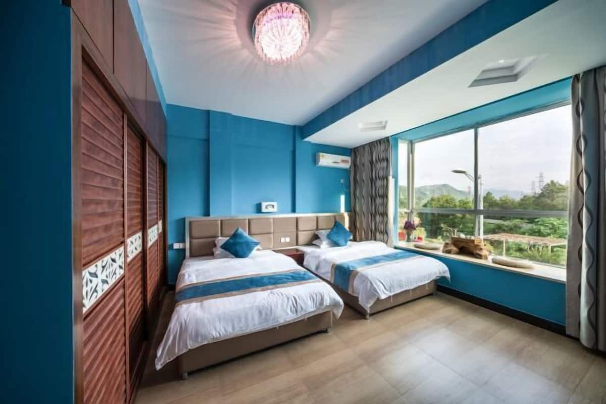 Una habitación de hotel con dos camas, un ventanal con vistas y una araña.