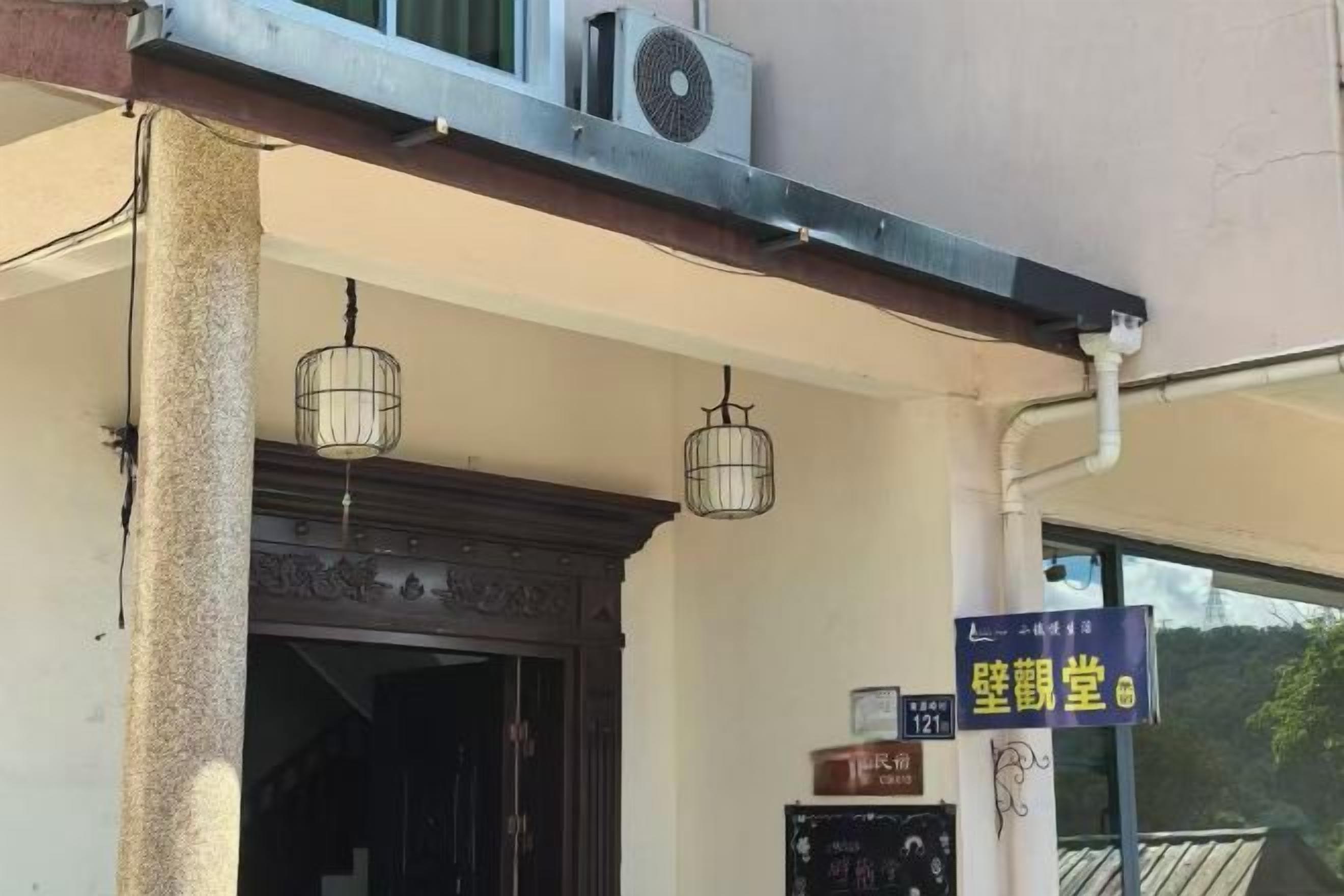 A building entrance with a sign, a water dispenser, and a security camera.