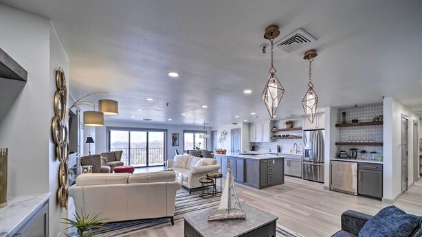 A modern open-plan living area with a sofa, a coffee table, and a dining area with a kitchen in the background. - Balcony & Lake View: Modern Condo in Monkey Island (Monkey Island)