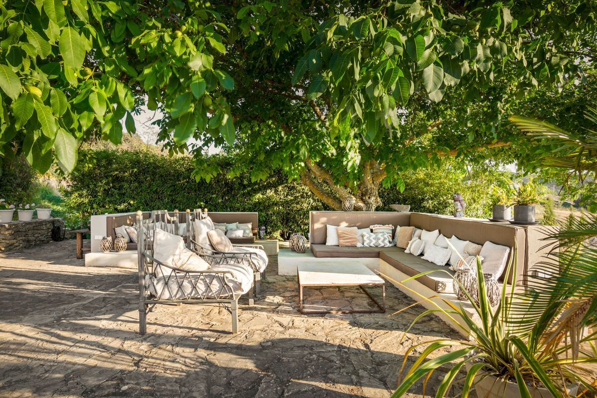 A sunlit outdoor seating area with a metal-framed sofa, a cushioned bench, and a coffee table.