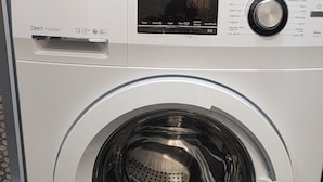 A front-loading Haier Direct Motion washing machine with a digital display and control panel. - Feel Welcome Barcelona (Cornella de Llobregat)