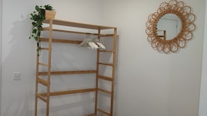 A wooden wardrobe with shelves, a mirror, and a hanging plant. - Feel Welcome Barcelona (Cornella de Llobregat)