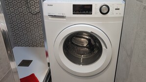 A front-loading Haier washing machine with a digital display and control panel. - Feel Welcome Barcelona (Cornella de Llobregat)