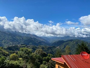 Un paisaje montañoso con una casa que tiene techo rojo y una antena parabólica.