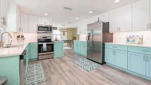 A modern kitchen with white cabinets, stainless steel appliances, and a teal countertop. - Coco Cay - Beautiful totally remodeled 4 bedroom with private pool (Holmes Beach)