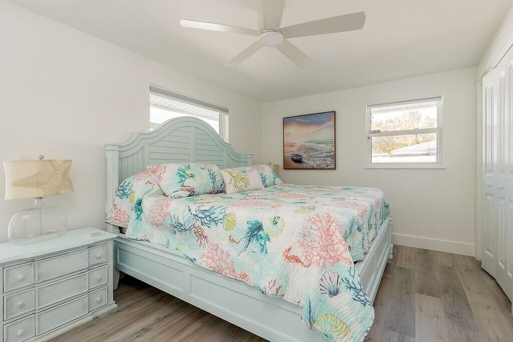 A bedroom with a bed, a nightstand, a lamp, and a ceiling fan.