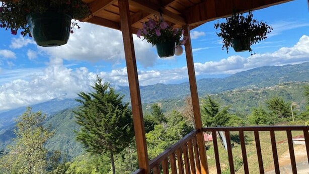 A wooden balcony with hanging flower pots, overlooking a mountainous landscape. - Red Princess Cabin - PERFECT view of the valley! (San José)