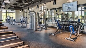 A gym with various exercise equipment, including treadmills, weight machines, and dumbbells. - Spacious 10-Bedroom Family Retreat Near Disney (Kissimmee)
