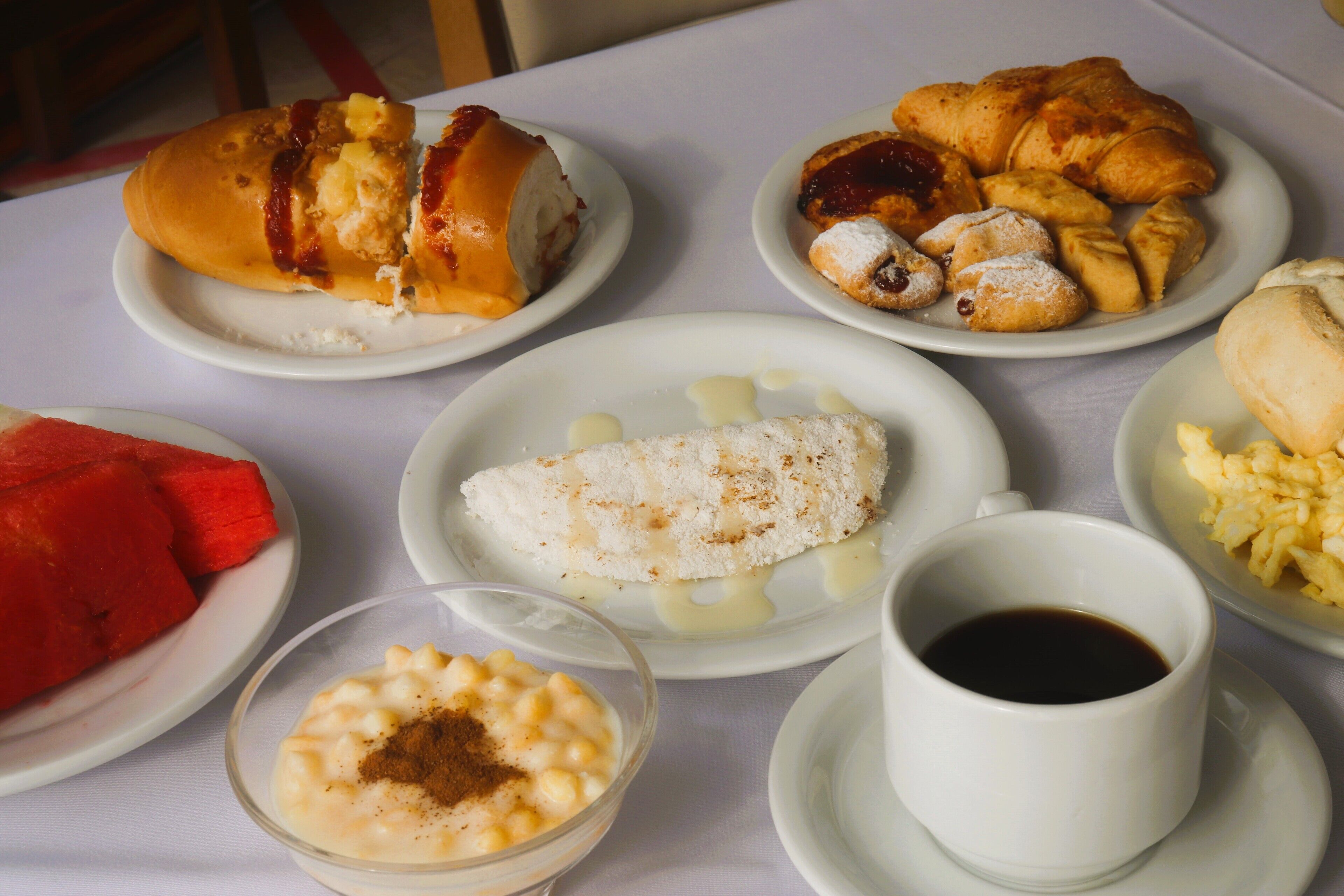 A table with various food items including croissants, a dessert, and a cup of coffee.