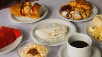 A table with various food items including croissants, a dessert, and a cup of coffee.